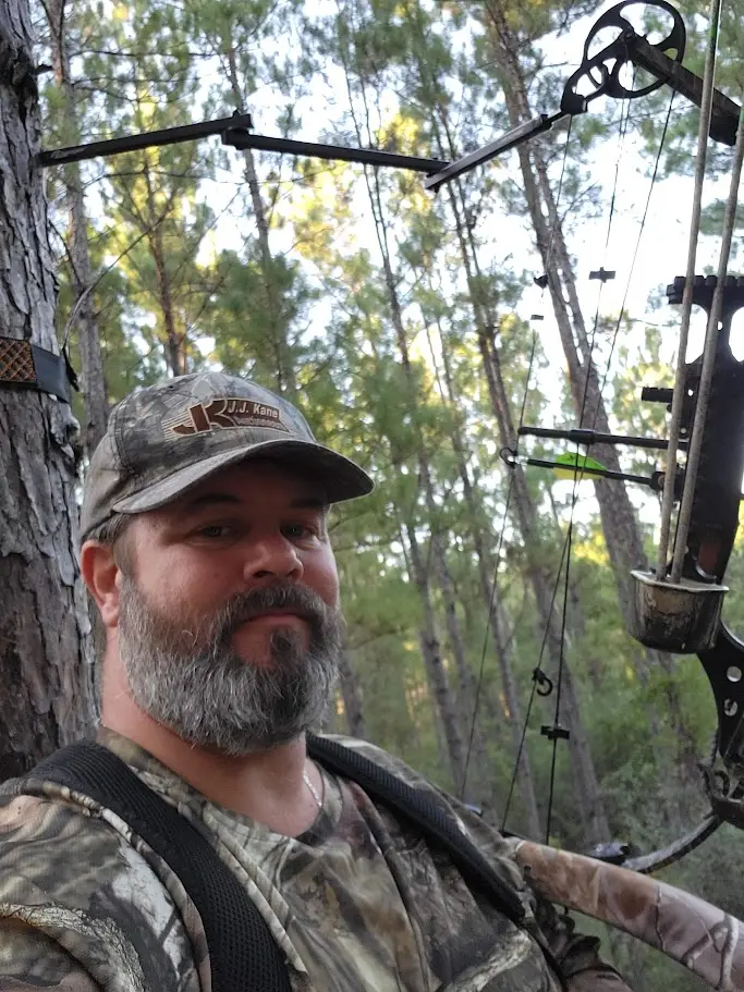 Jared Braddock, outdoors copywriting hunter in a tree stand with a compound bow